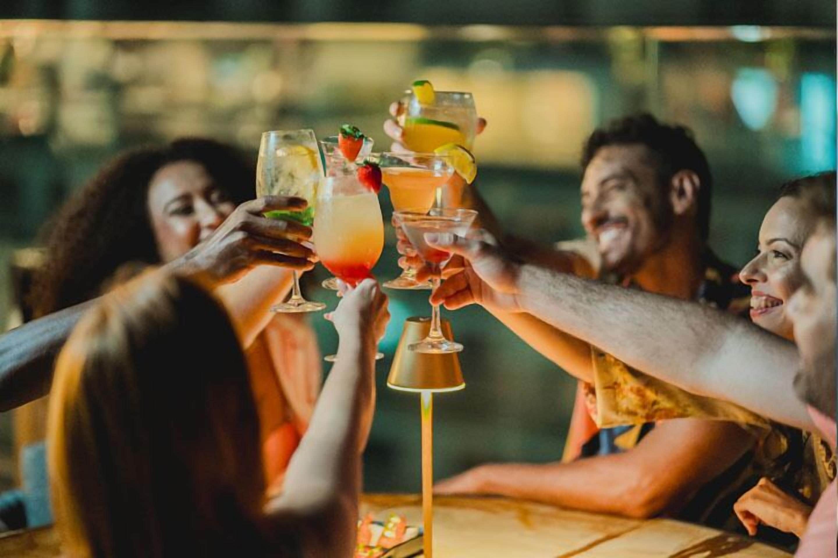 Um grupo de pessoas brindando com bebidas à mesa.