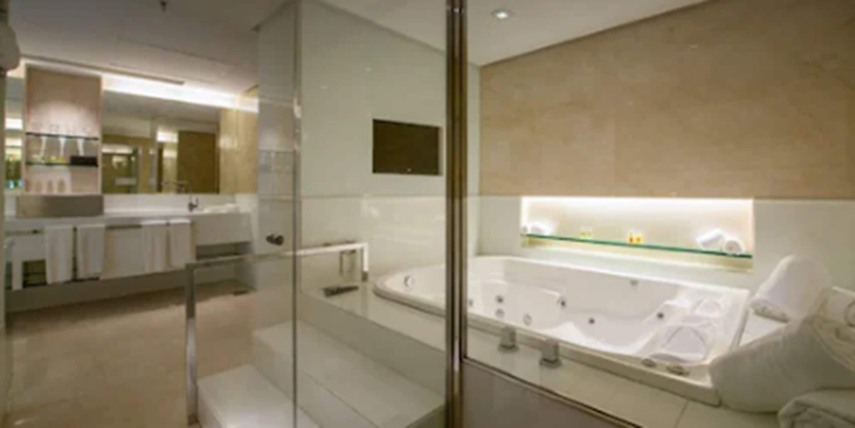 A modern bathroom with a glass shower enclosure, a large bathtub, and a vanity with a mirror.