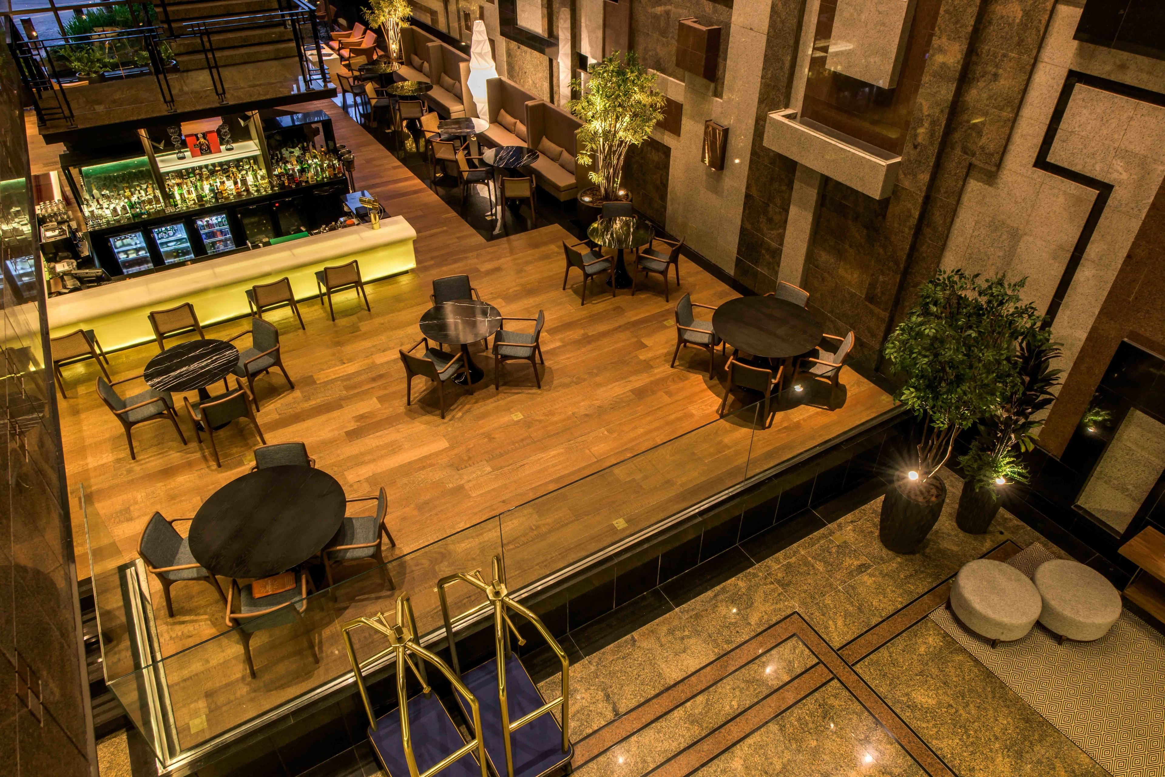 A spacious indoor area with multiple seating arrangements, a bar, and a staircase leading to an upper level.