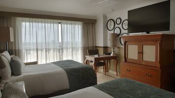 A hotel room with two beds, a desk, a television, and a cabinet.