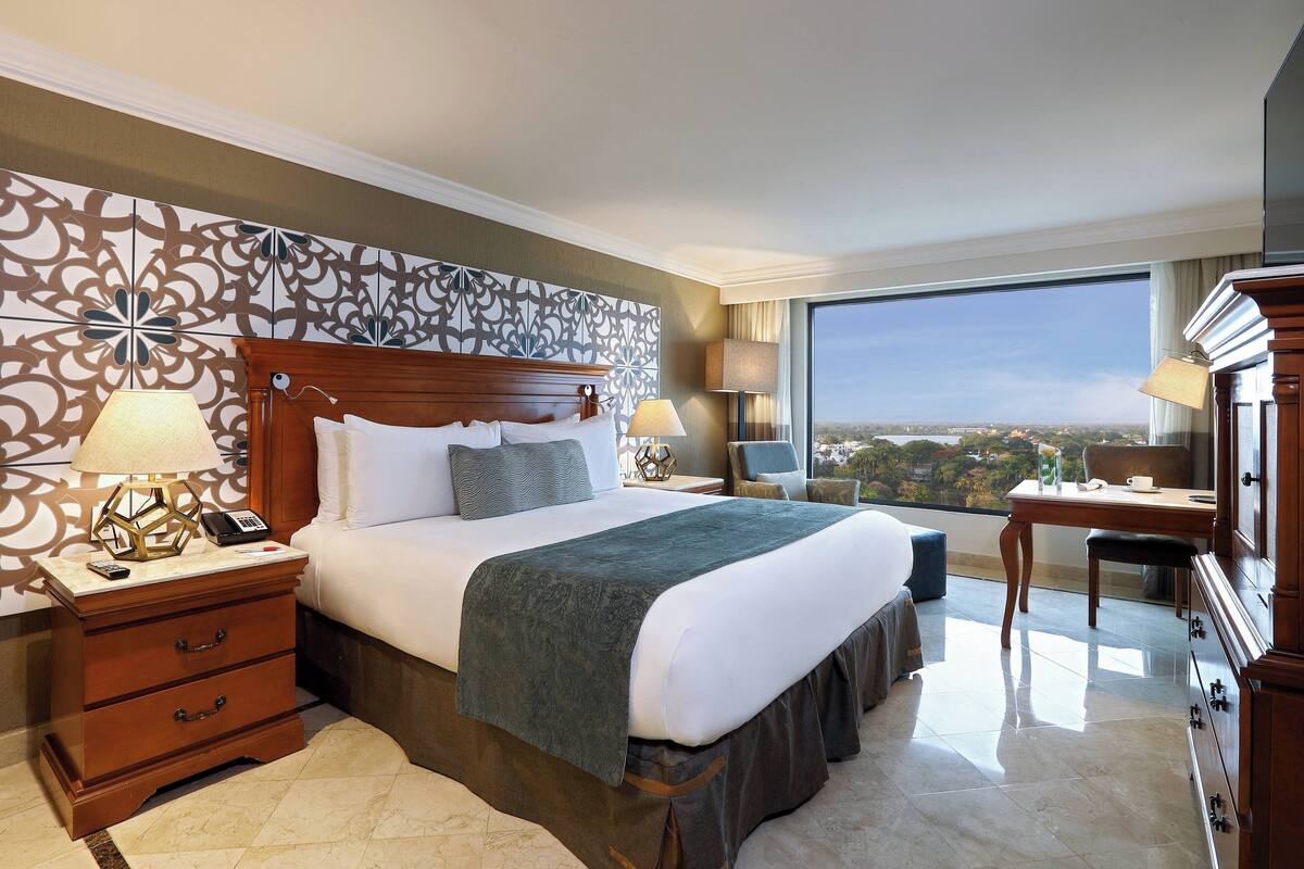 Une chambre d’hôtel avec un grand lit, un bureau, une chaise et une vue sur la ville.