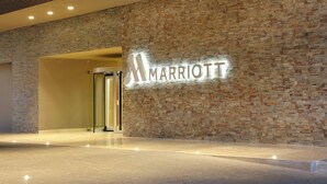 A Marriott hotel entrance with a stone wall and a modern, illuminated sign.