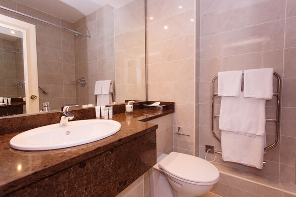 Un baño moderno con lavamanos de mármol, inodoro y perchero.