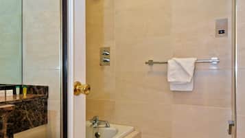 A bathroom with a glass shower door, a sink, and two toilets.