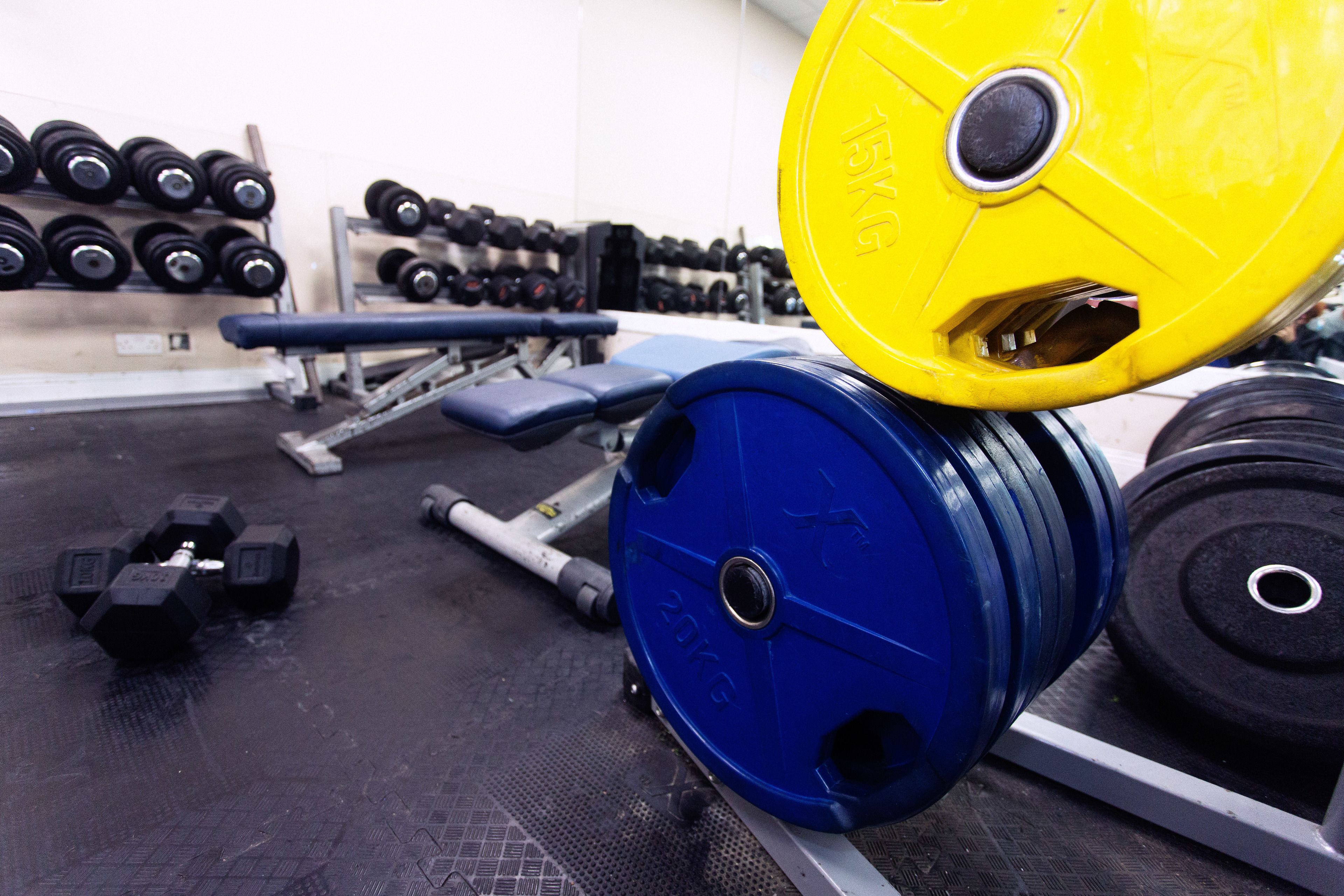 A gym with weightlifting equipment, including barbells and dumbbells.