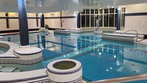Una piscina interior con varias pistas de natación, azulejos decorativos y una estatua.