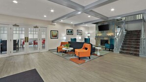 A spacious lobby with a modern staircase, seating area with orange and teal chairs, and a fireplace. - Comfort Inn & Suites Santee (Santee)