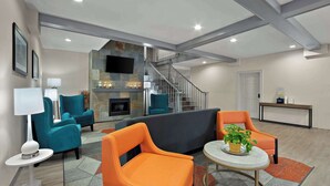 A modern living room with teal and orange chairs, a grey sofa, a fireplace, and a staircase. - Comfort Inn & Suites Santee (Santee)
