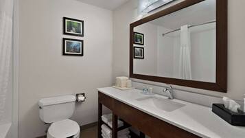 A bathroom with a white toilet, a sink with a mirror, and two framed pictures on the wall.