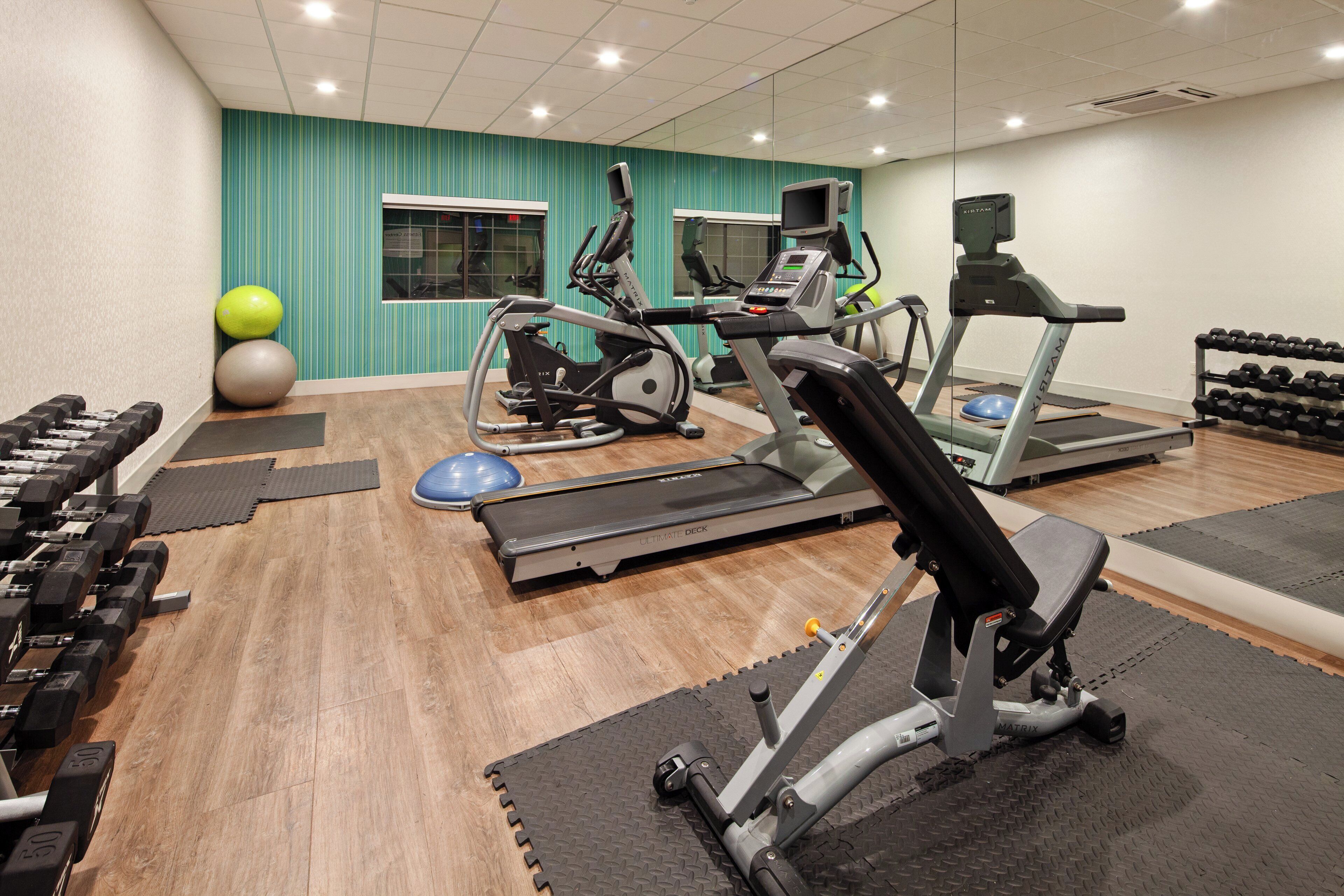 A gym with treadmills, elliptical machines, and free weights.