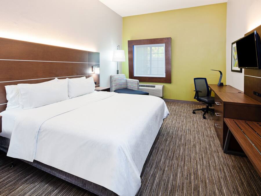 Une chambre d’hôtel avec un grand lit, un bureau, une chaise, une télévision et une fenêtre.