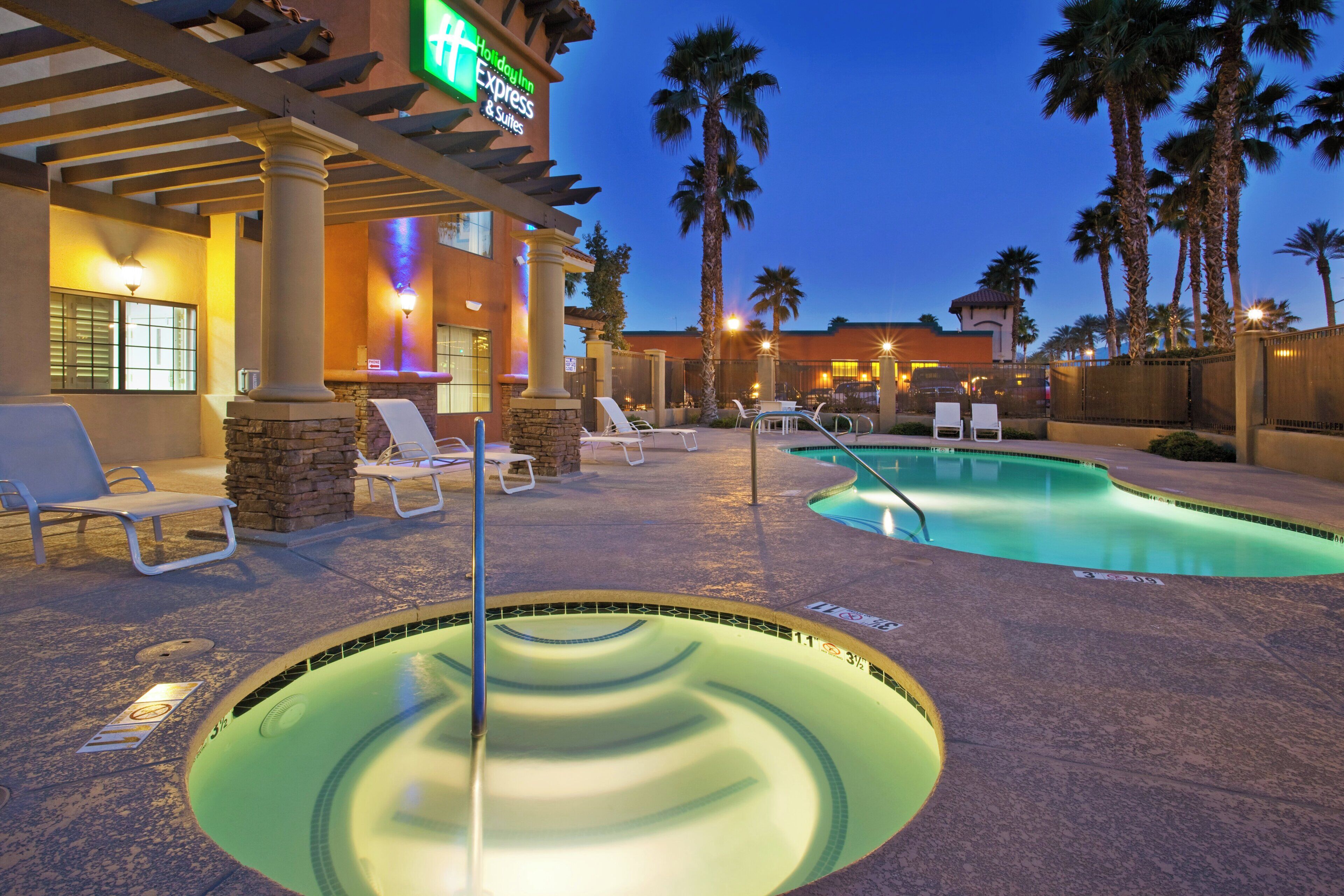 A hotel pool area with lounge chairs and a hot tub.