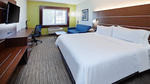 A hotel room with a large bed, a desk with a flat-screen TV, a blue chair, a small table, and a window with a view. - Holiday Inn Express & Suites Rancho Mirage - Palm Spgs Area by IHG (Rancho Mirage)