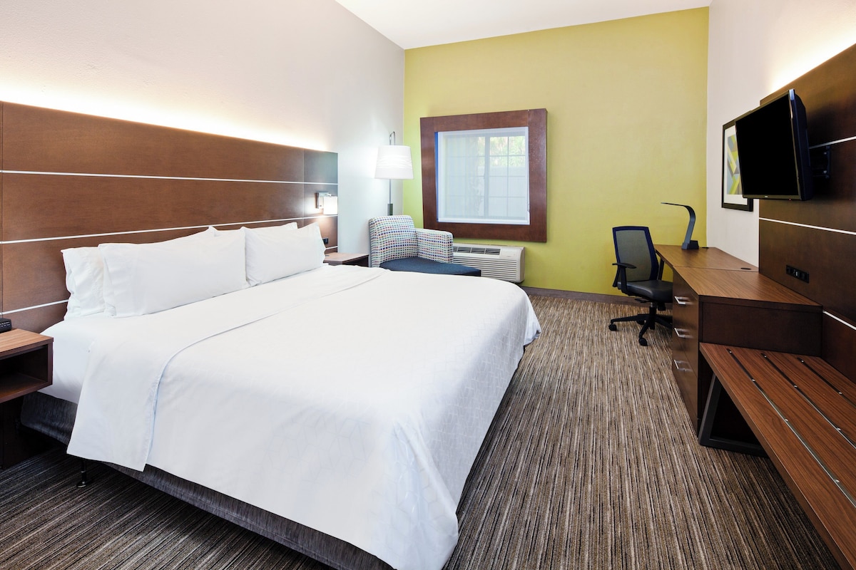 Une chambre d’hôtel avec un grand lit, un bureau, une chaise, une télévision et une fenêtre.