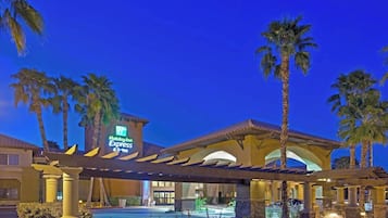 Un hôtel Holiday Inn Express doté d’une piscine, de palmiers et d’une entrée abritée.