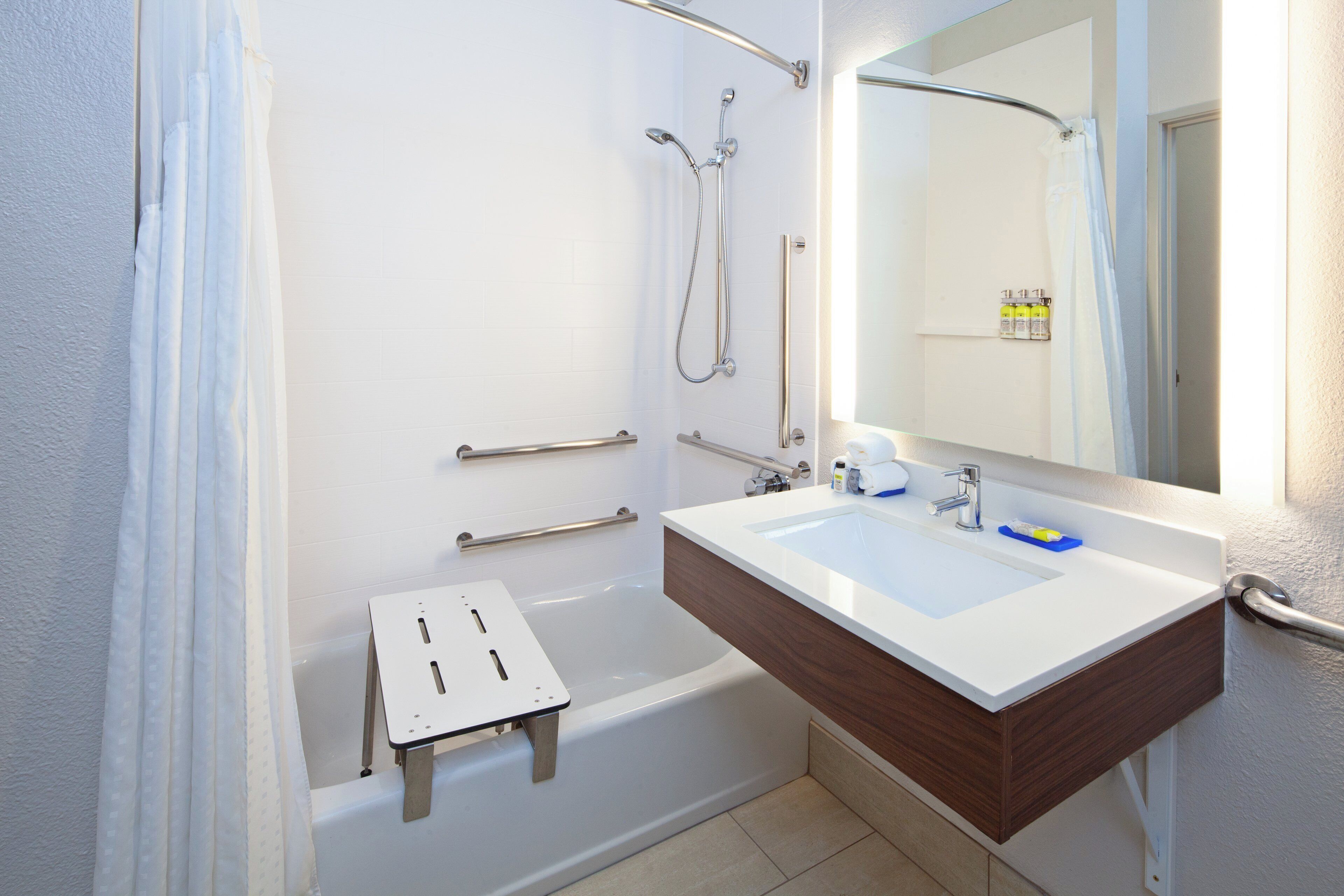 Ein modernes Badezimmer mit einer weißen Badewanne, einem großen Spiegel und einem hölzernen Waschtisch.
