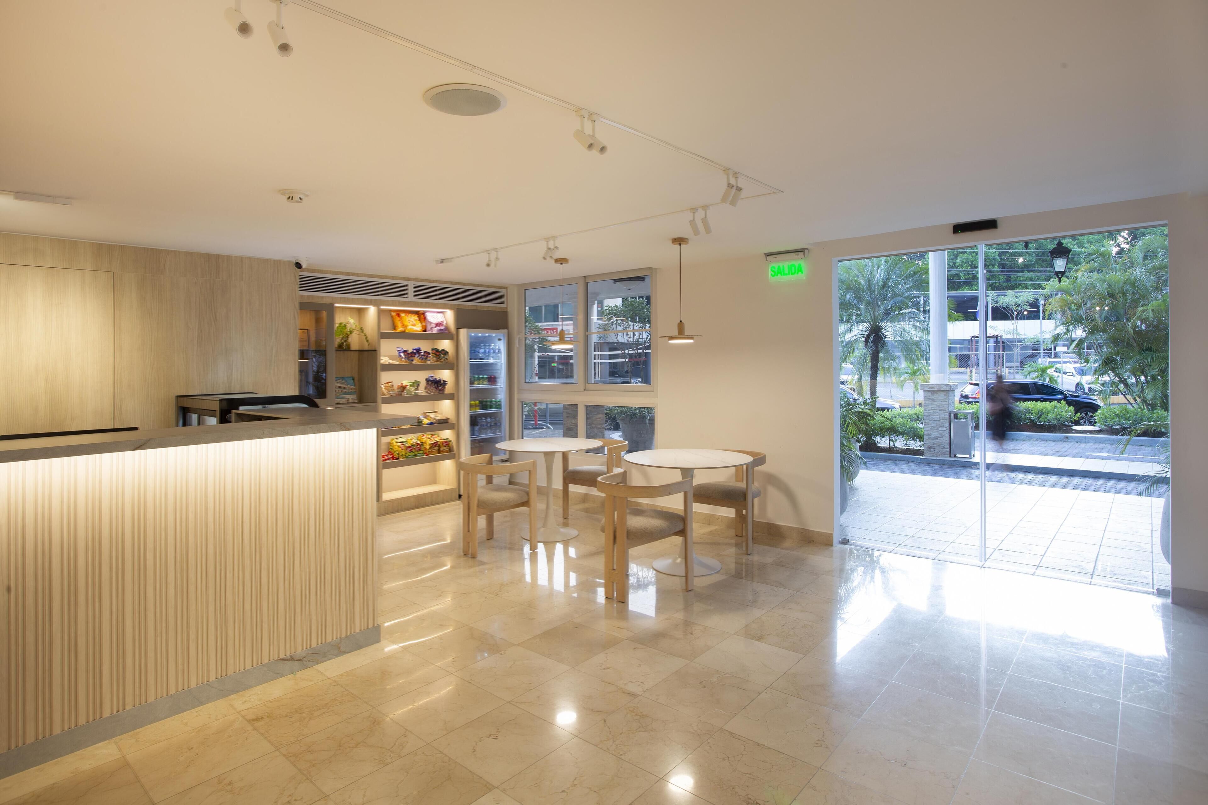 Un interior moderno con un mostrador de recepción, zona de estar y grandes ventanales con vistas al exterior.