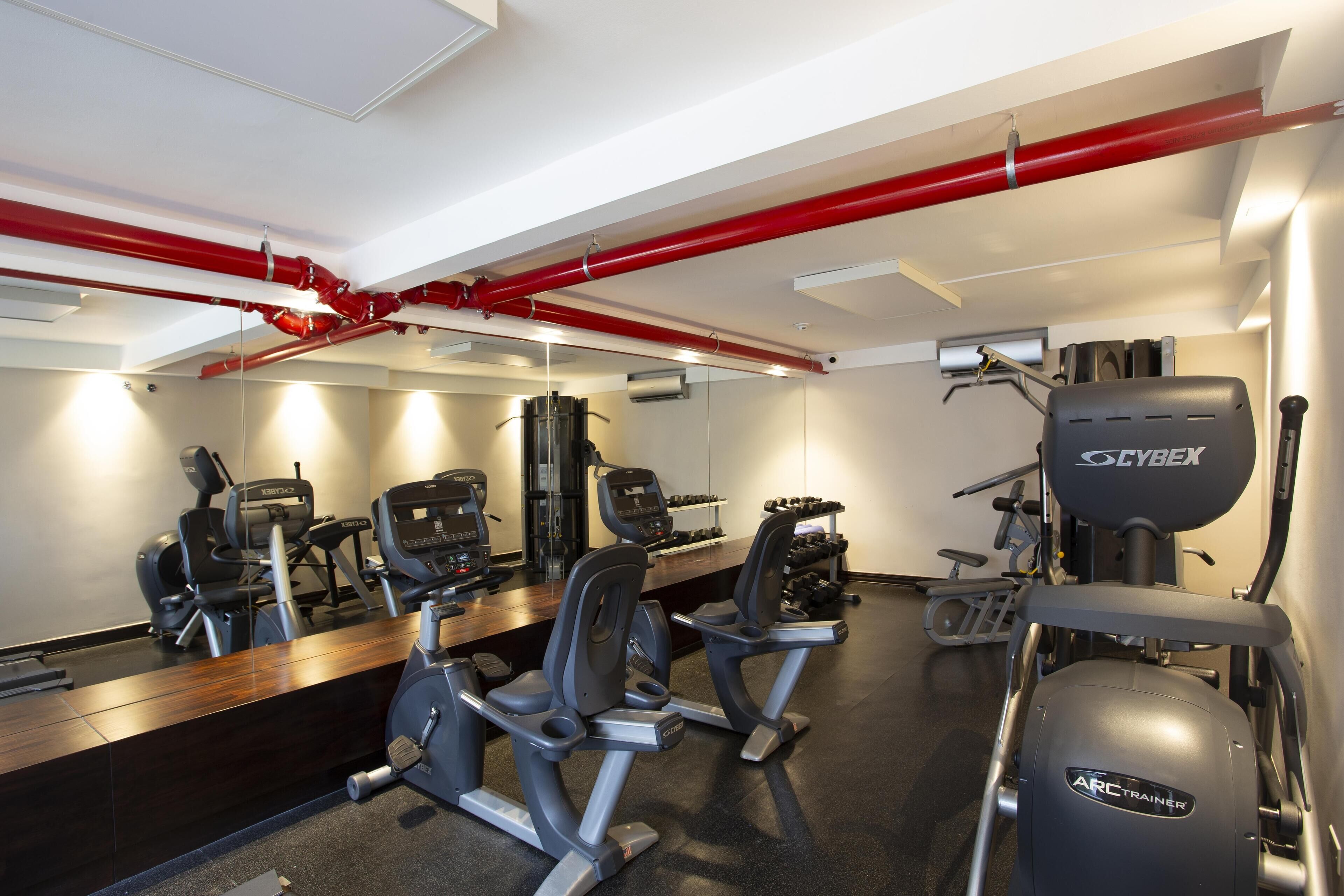A gym with cardio machines, weight benches, and a Cybex elliptical.