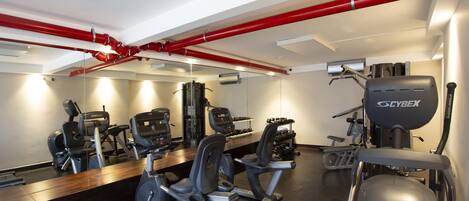 A gym with cardio machines, weight benches, and a Cybex elliptical.