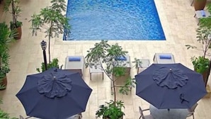 An outdoor swimming pool with lounge chairs and umbrellas, surrounded by potted plants. - Best Western El Dorado Panama Hotel (Panama City)