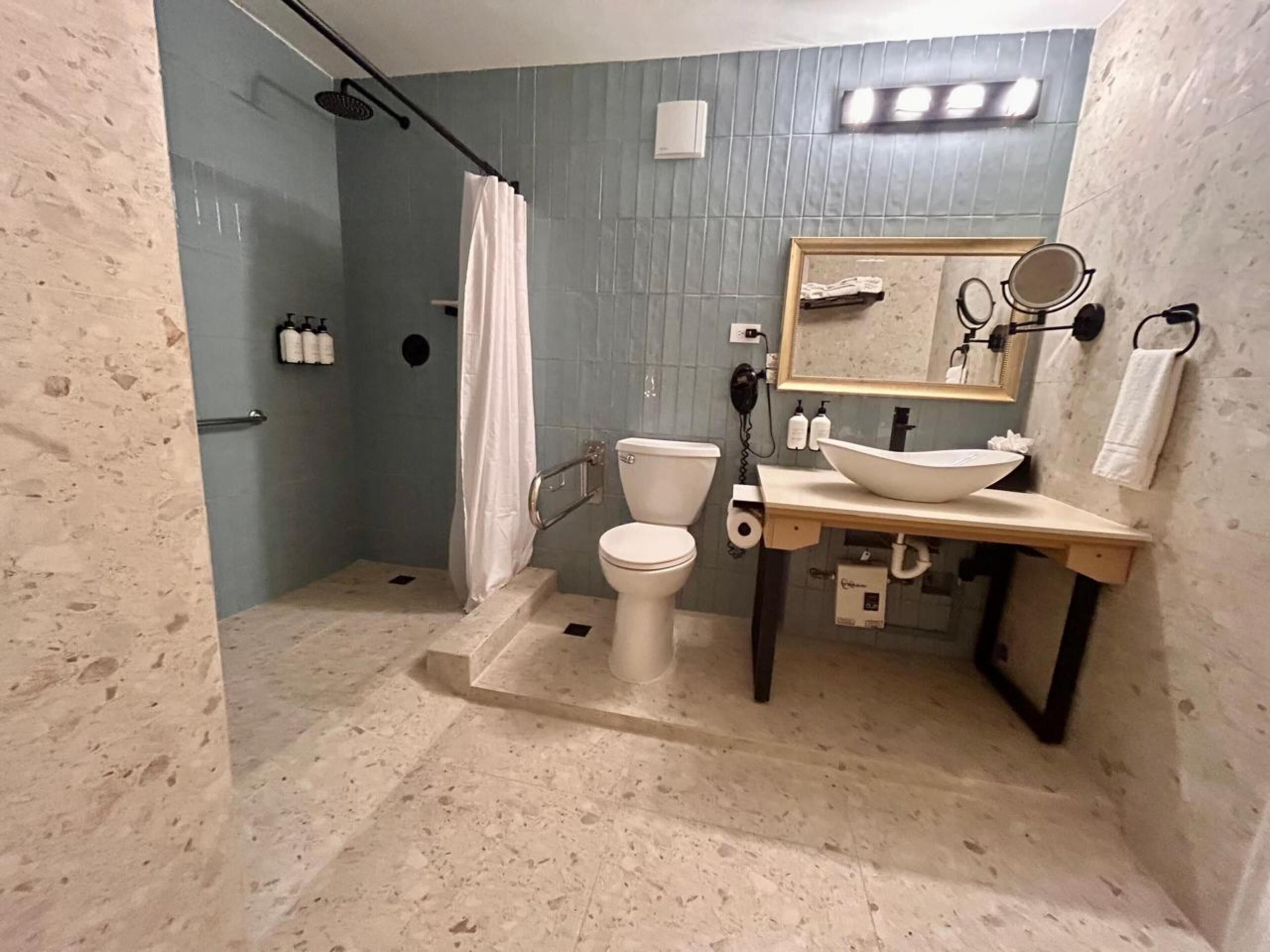 A bathroom with a shower, toilet, sink, and mirror.