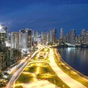 A nighttime cityscape with high-rise buildings, a waterfront, and a well-lit road with light trails. - Best Western El Dorado Panama Hotel (Panama City)