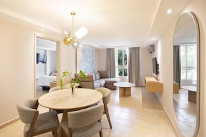 A modern living room with a round dining table, comfortable seating, a sofa, a TV, and a large mirror. - Best Western El Dorado Panama Hotel (Panama City)