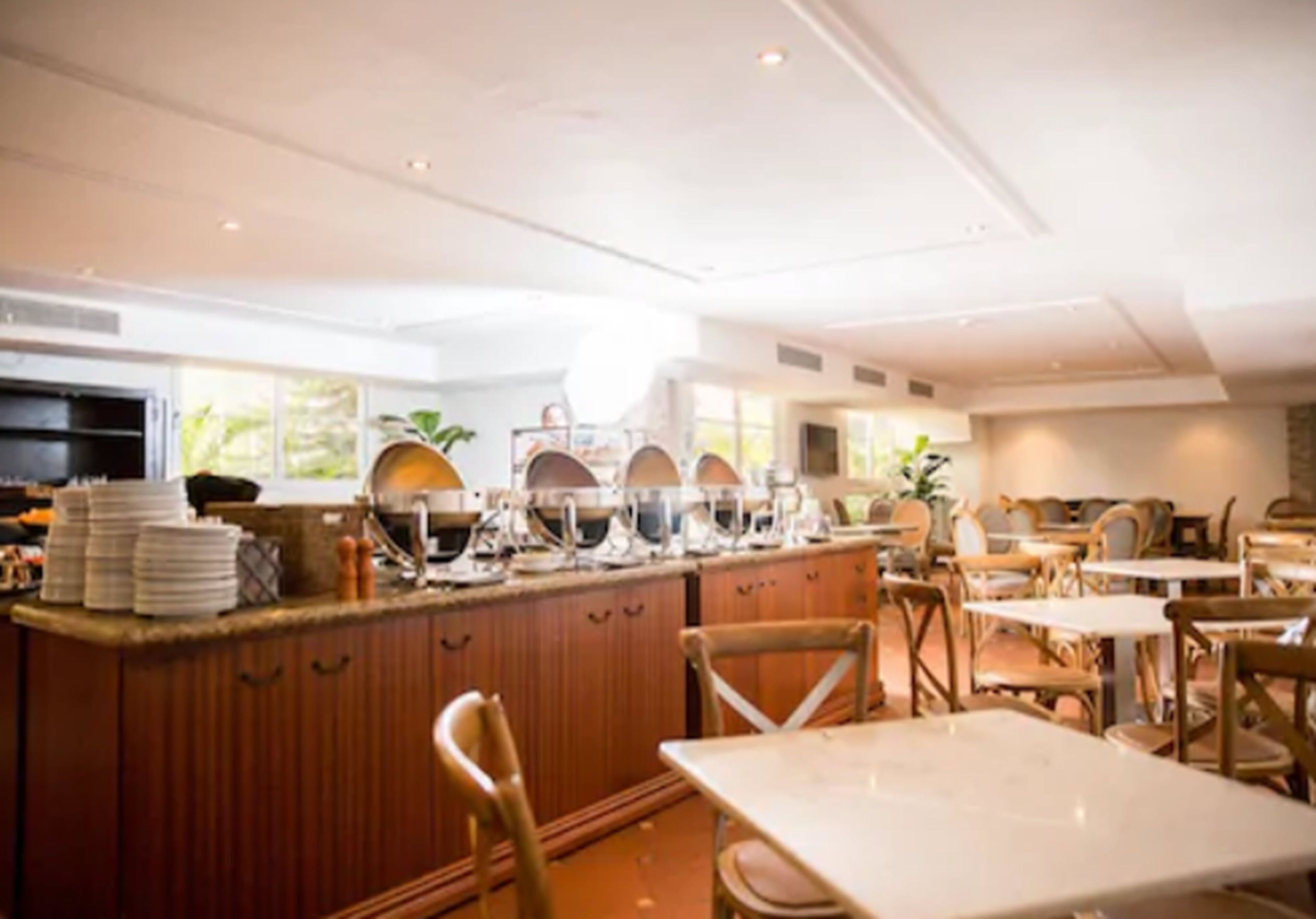 A modern kitchen with a central island, wooden cabinets, and a dining area with tables and chairs.
