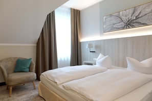 Une chambre d’hôtel avec un grand lit, une chaise, une lampe et une œuvre d’art accrochée au mur.