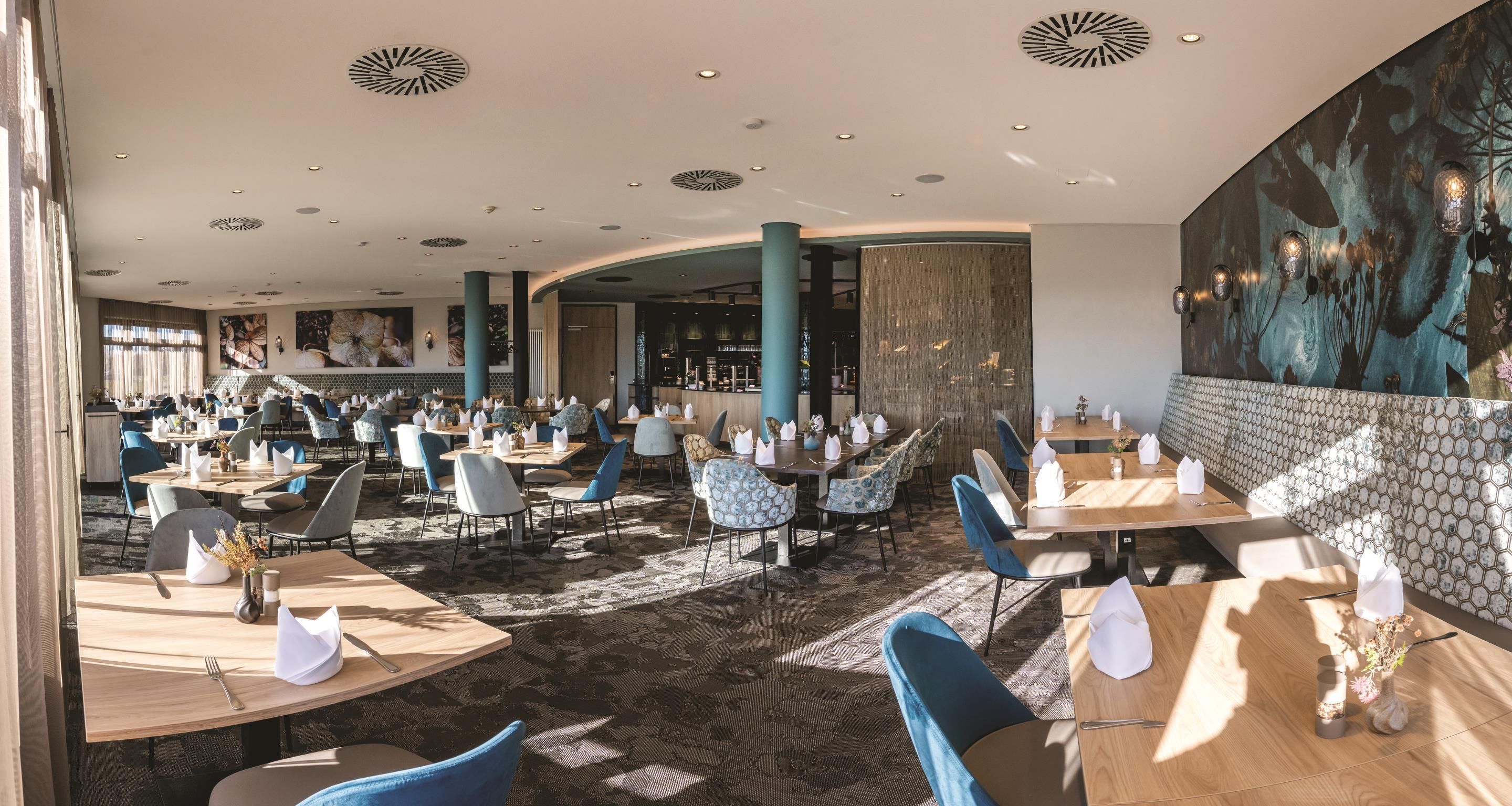 A spacious restaurant with multiple dining areas, including a bar and a seating area with a view of the cityscape.