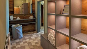 Un baño con piso a cuadros, un espejo, un lavamanos y repisas con toallas.