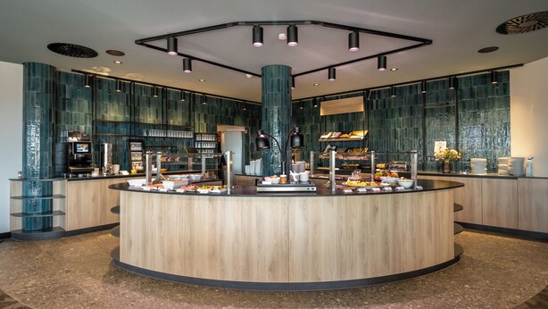 Una barra de desayuno moderna con una isla central, rodeada de asientos y un ventanal grande.