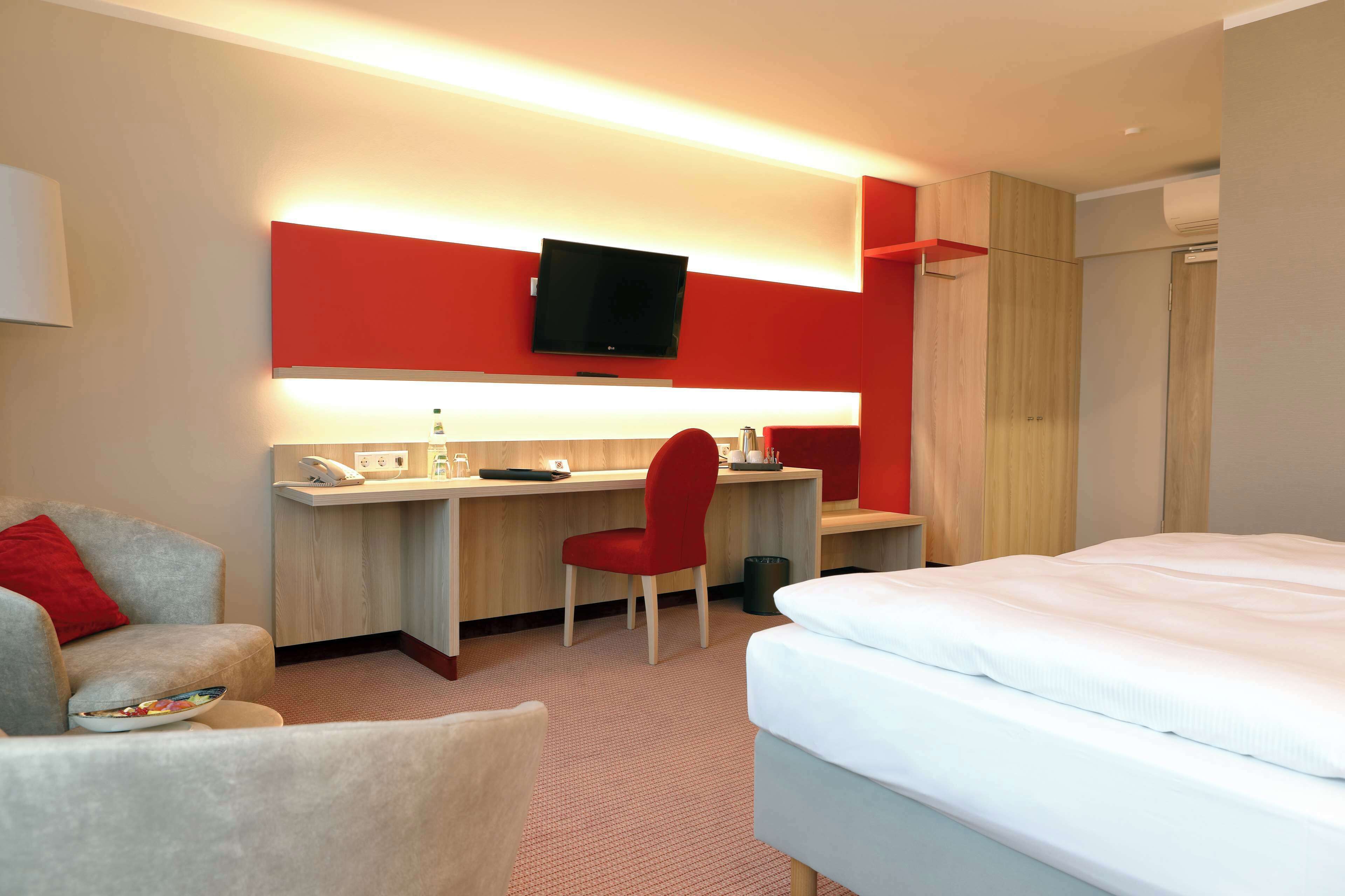Une chambre d’hôtel comprenant un lit, un bureau avec une chaise, une télévision et une armoire.