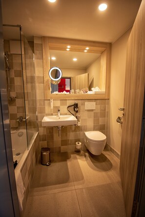 A modern bathroom with a glass shower enclosure, a sink, a toilet, and a mirror with a round light. - Best Western Hotel Erfurt-Apfelstaedt (Nesse-Apfelstädt)