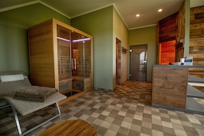 A room with a checkered floor, a wooden cabinet, a wicker chair, and a small round table. - Best Western Hotel Erfurt-Apfelstaedt (Nesse-Apfelstädt)