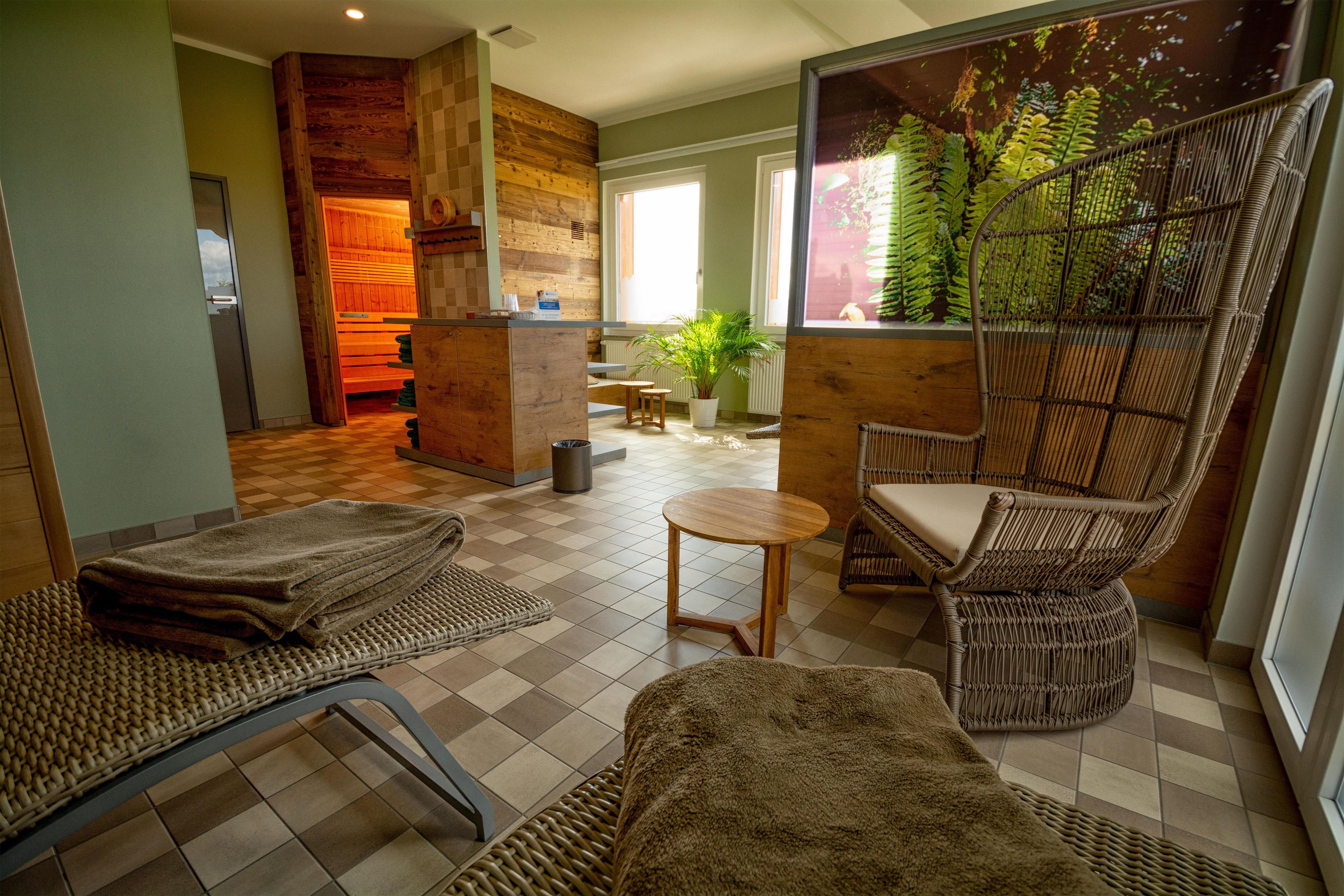 Un área de spa con suelo a cuadros, muebles de mimbre, una mesita y una planta en la pared.
