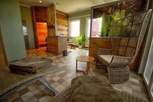 Un área de spa con suelo a cuadros, muebles de mimbre, una mesita y una planta en la pared.