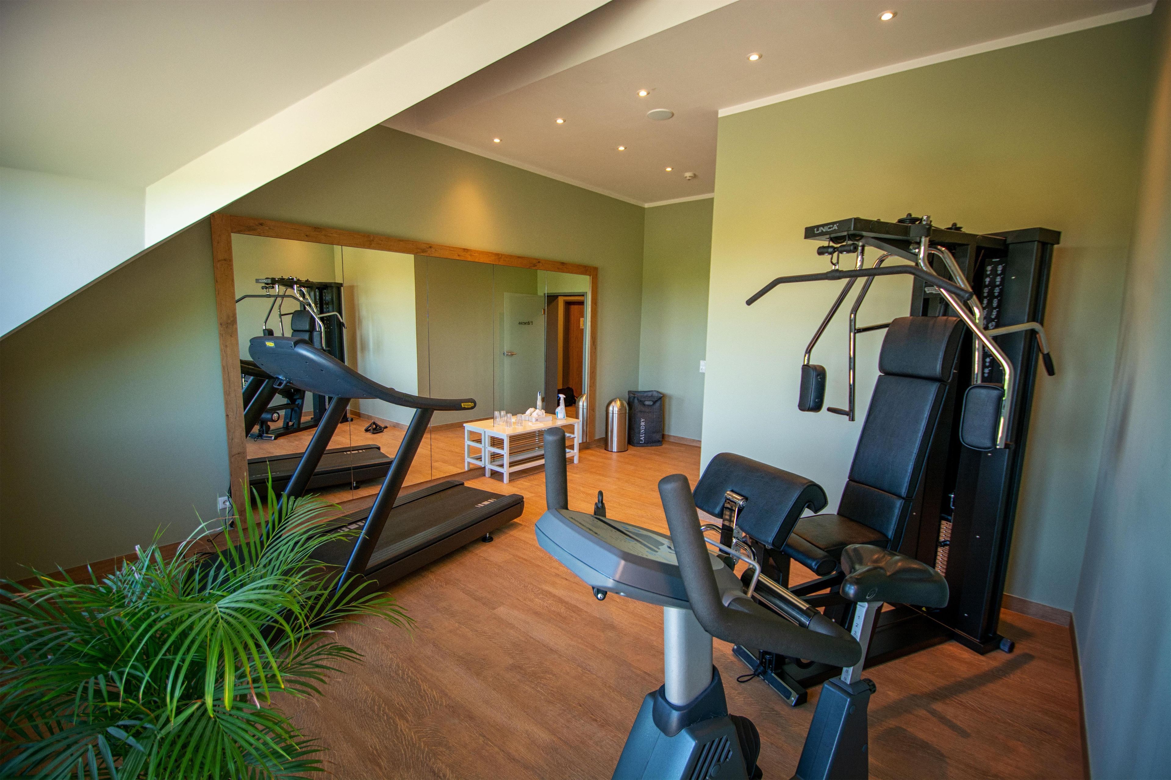 A home gym with exercise equipment, a mirror, and a staircase leading to an upper level.