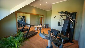A home gym with exercise equipment, a mirror, and a staircase leading to an upper level.