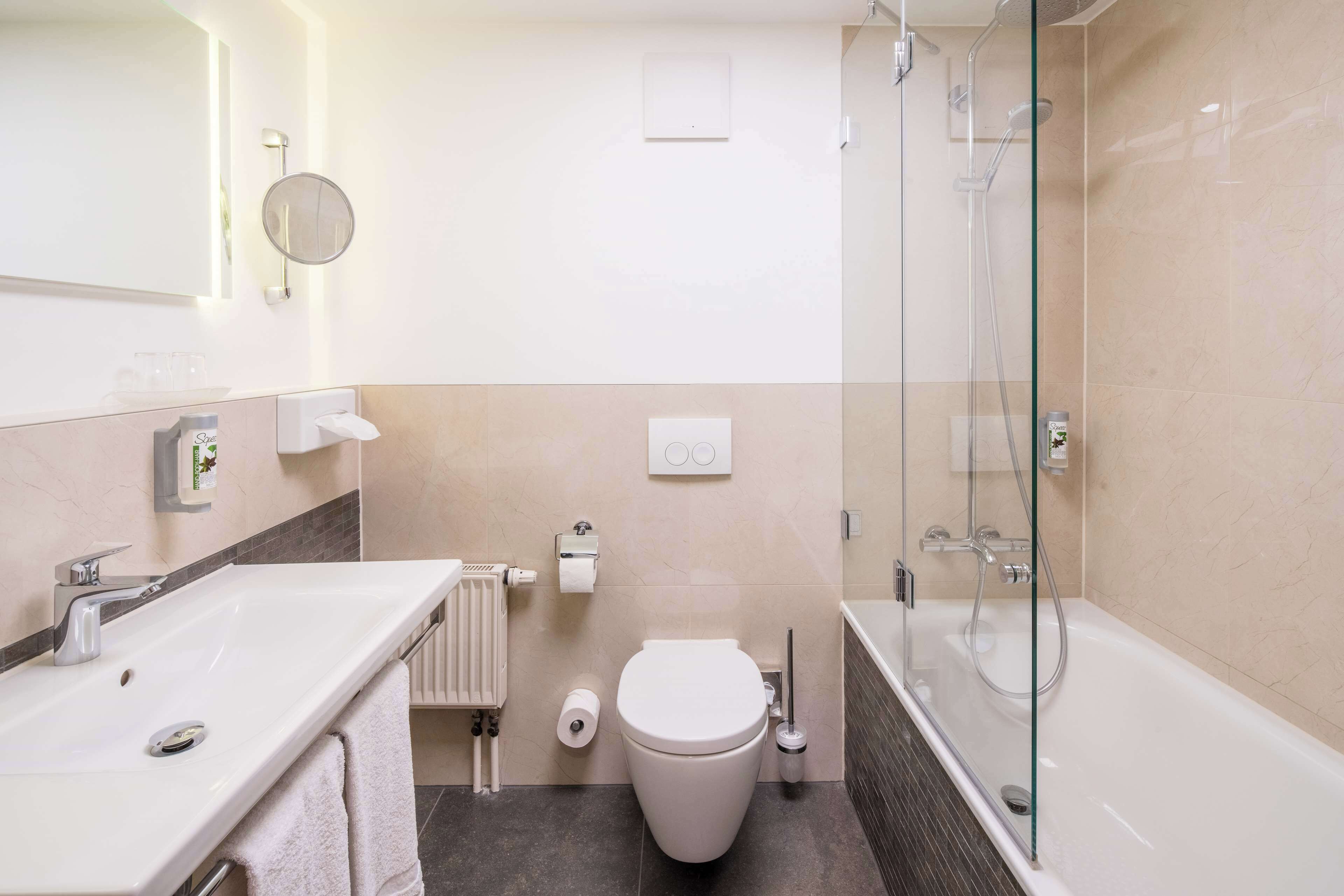A modern bathroom with a glass-enclosed shower, a white sink, and a toilet.
