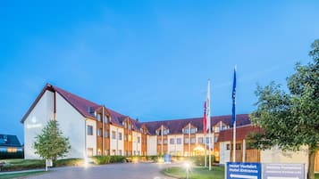 A hotel with a modern design, featuring a central courtyard, multiple buildings, and a flagpole.