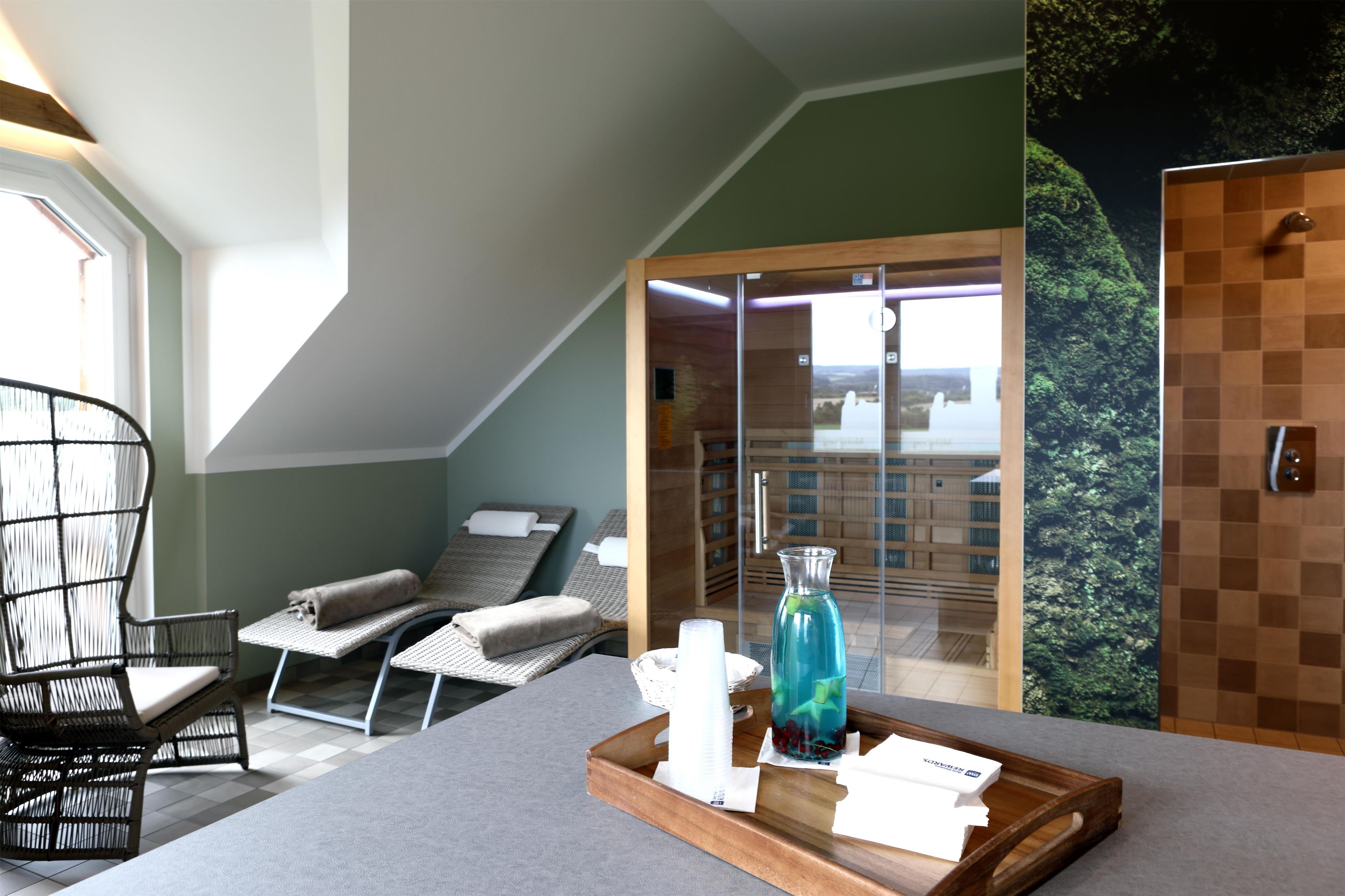 Une pièce comprenant un lit, une chaise, un plateau avec divers objets, et une vue sur un bâtiment à travers une porte vitrée.