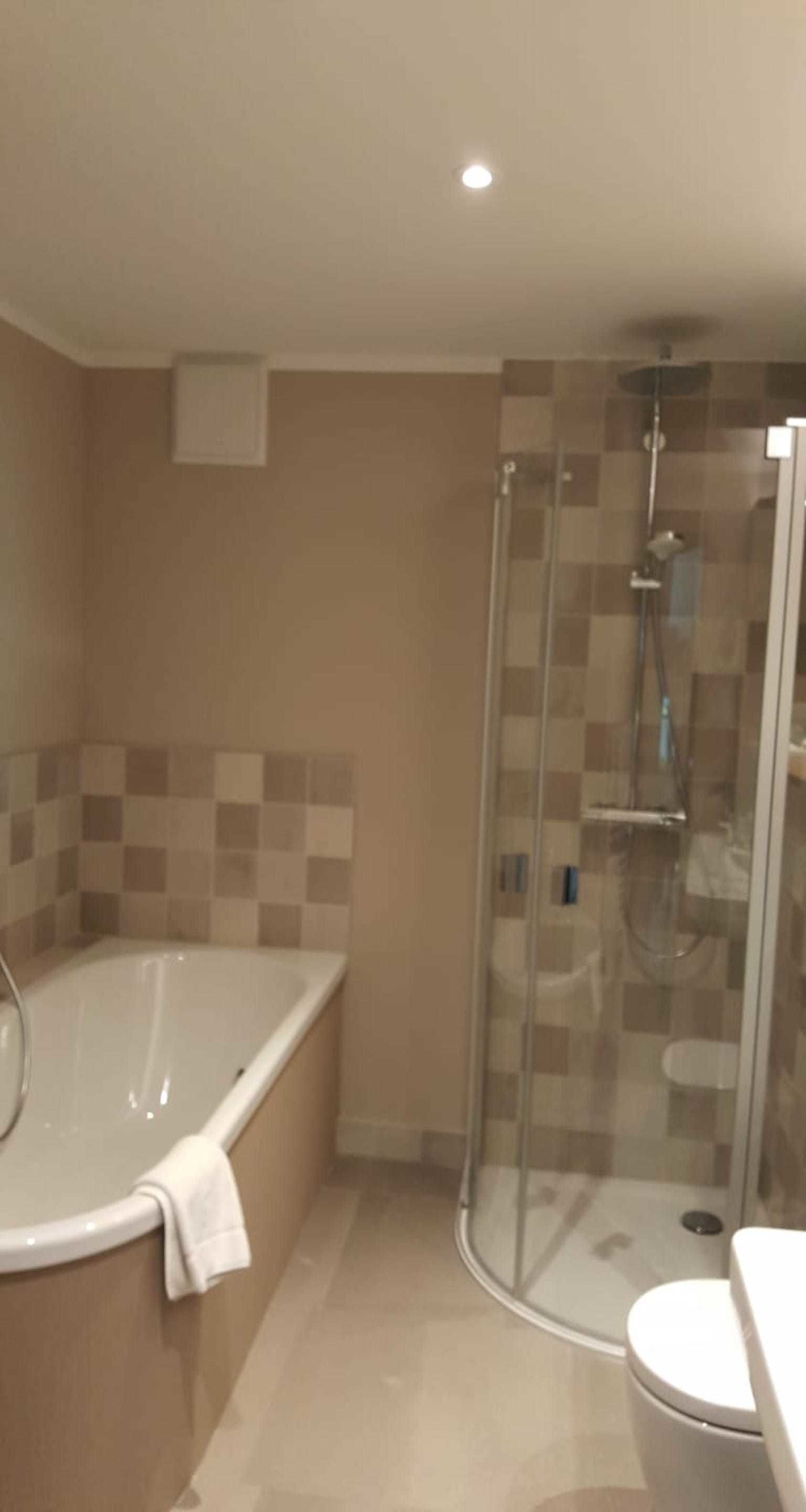 Een badkamer met een douchecabine van glas, een vrijstaand bad en een toilet.