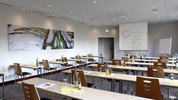 A conference room with multiple tables, chairs, and a large abstract painting on the wall.