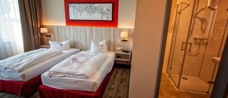 Une chambre d’hôtel avec deux lits, une douche et un mur d’accent rouge.