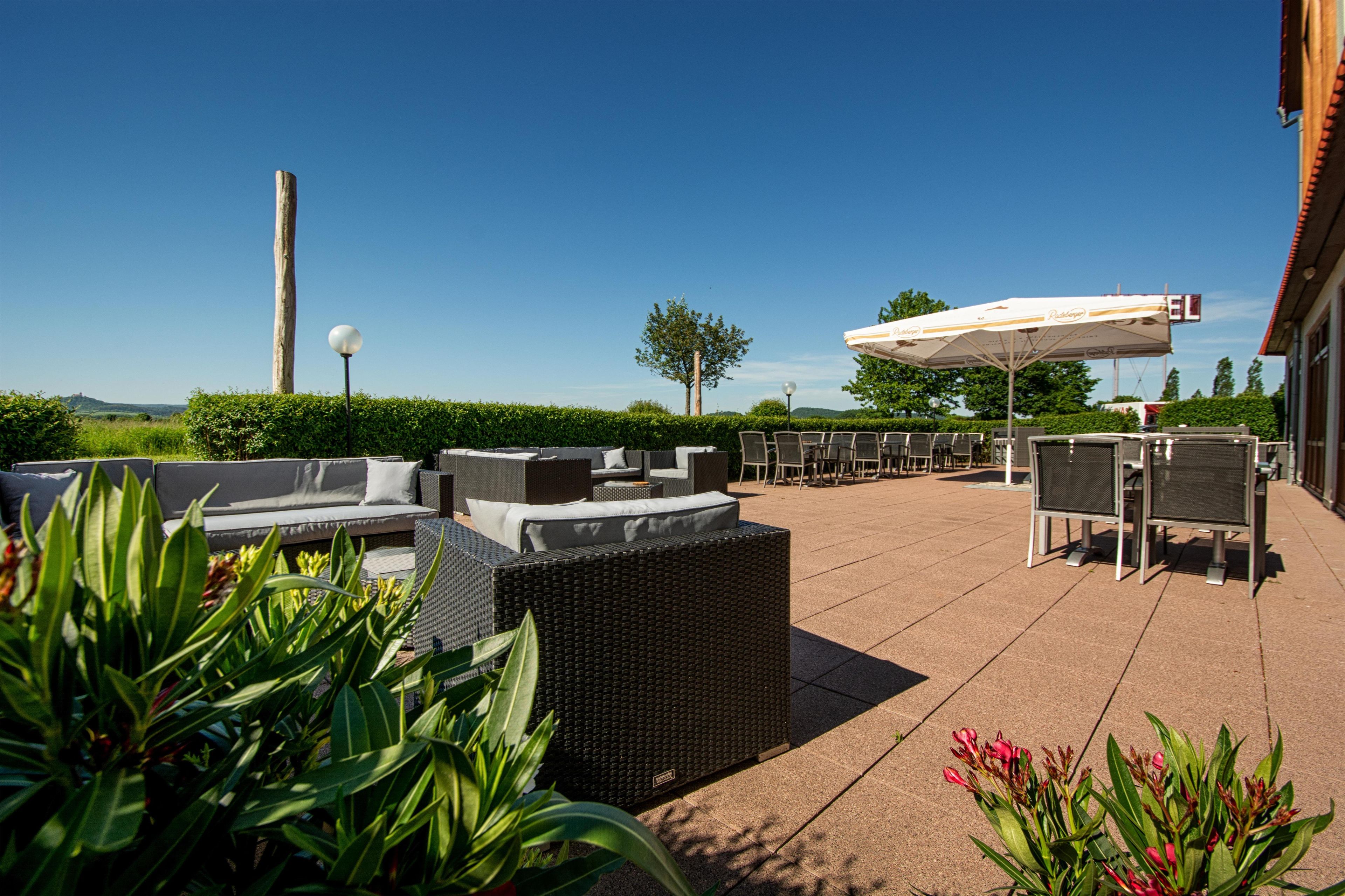 An outdoor seating area with wicker furniture and a white umbrella.