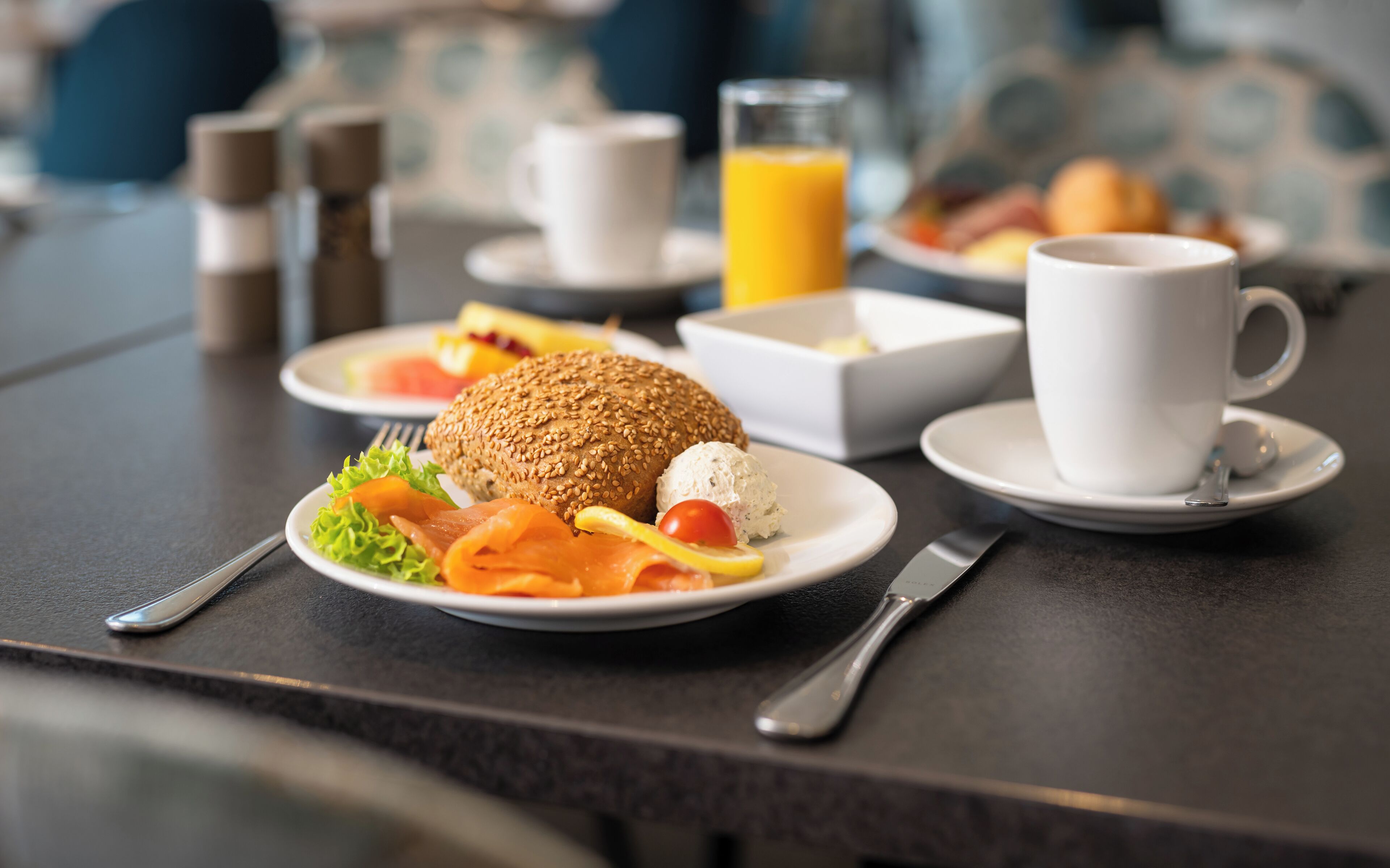 Ein Frühstückstisch mit Sandwich, Salat und einem Glas Orangensaft.