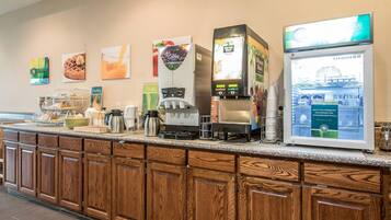 A breakfast bar with coffee machines, a refrigerator, and various food items.