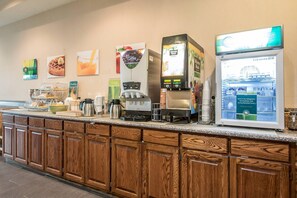 A breakfast bar with coffee machines, a refrigerator, and various food items. - Quality Inn & Suites East Troy I-43 (East Troy)