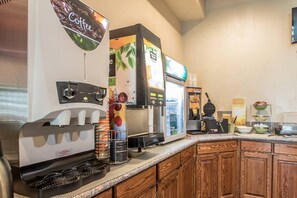 Um espaço com estação de café, máquina de café, bebedouro e dispensador de bebidas.
